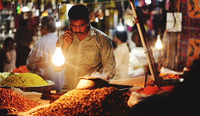 Market vendor answering phone while working at illuminated market stall (photo)