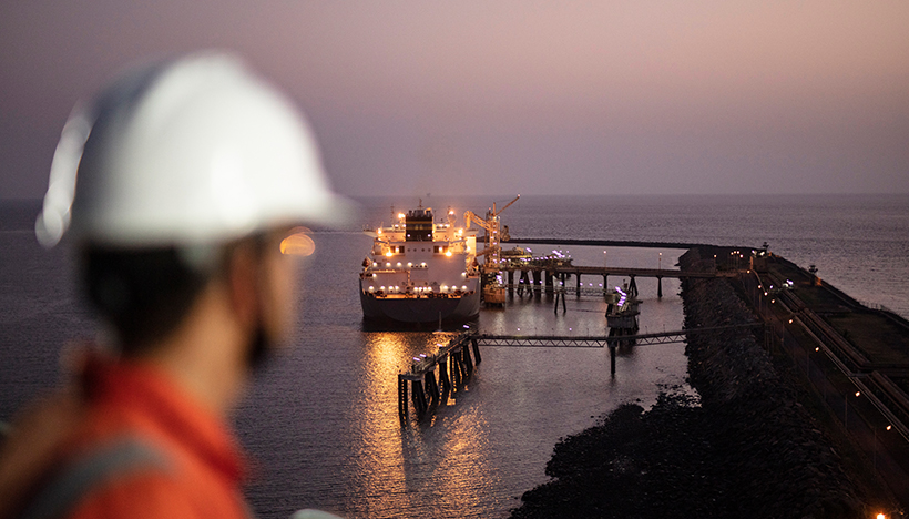 Shell employee looking at an LNG tanker at sunset (photo)