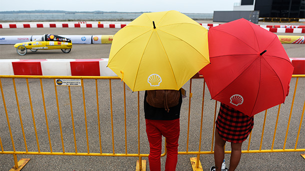 two people with a yellow and a red umbrella watching the motor-racing (photo)