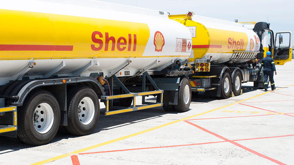 Man in working clothes walks towards the open door of a Shell tanker truck with trailer (photo)