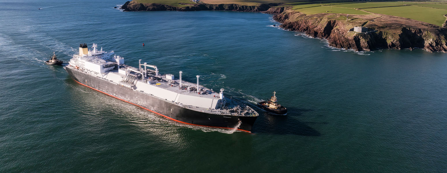 Aerial view of an LNG vessel passing by cliffs and green fields (photo)