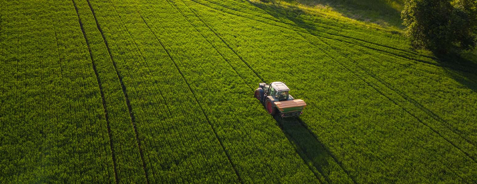 Aerial view of a tractor working a verdant hilly field (photo)