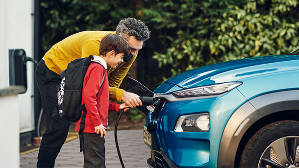 Father assisting his son with charging an electric car