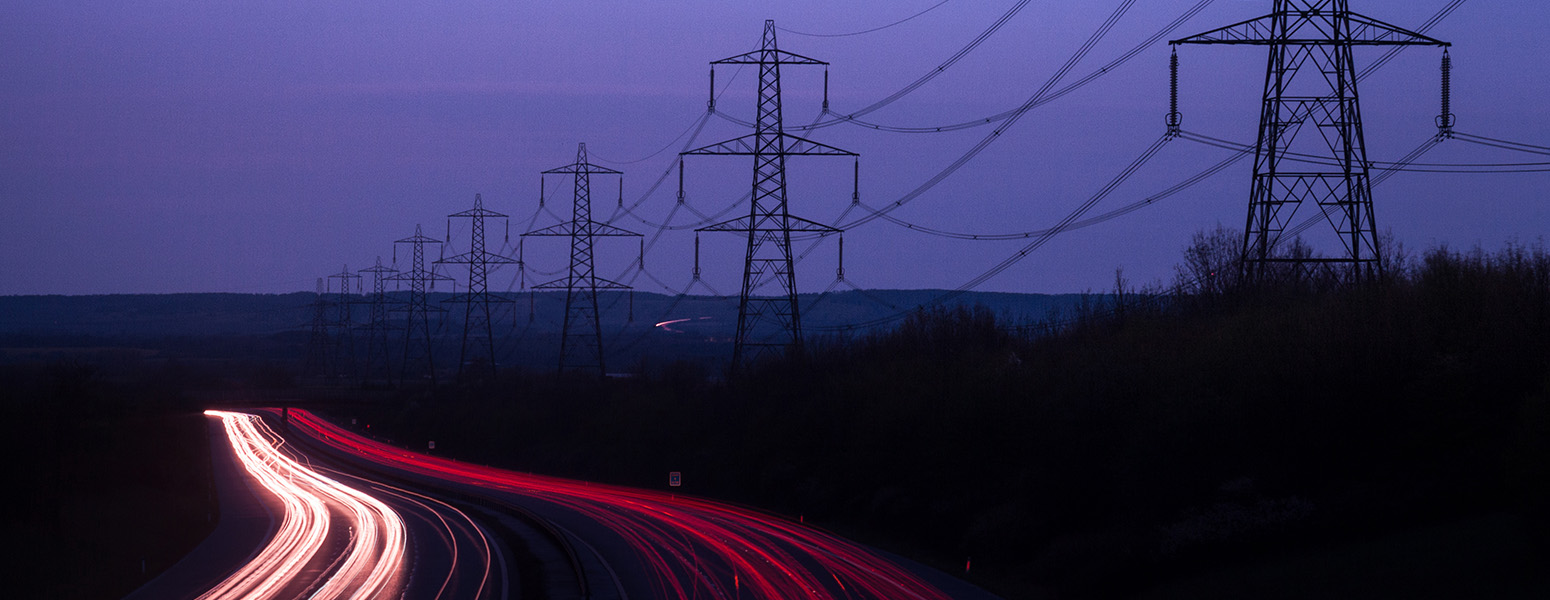 Electricity pylons and red and white lights from cars at night