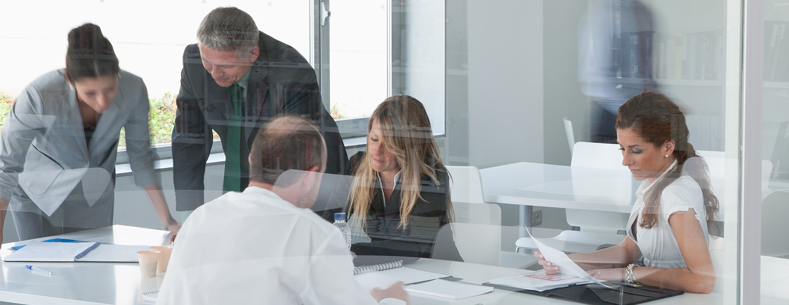 group of business people discussing documents on a table in a glass office