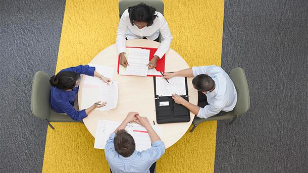 group of business people discussing documents on a table in a glass office