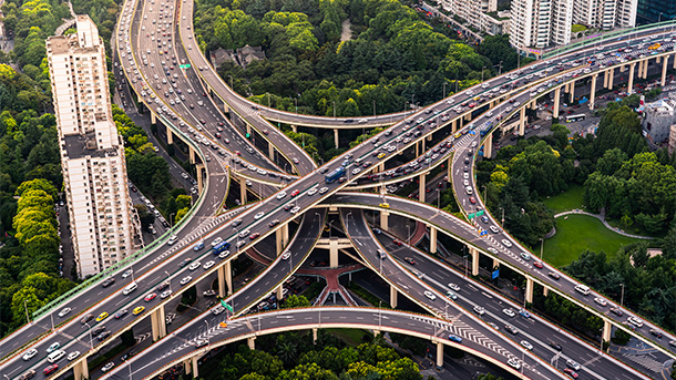 Aerial view of a motorway intersection surround by trees and skyscrappers