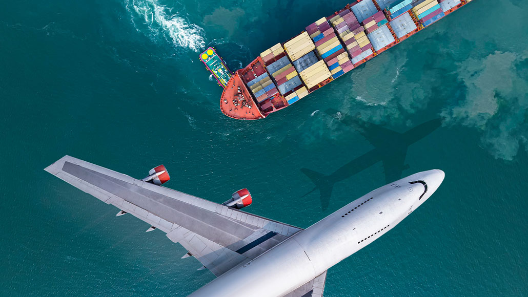 Aerial view of an airplane seen flying over a cargo ship (photo)