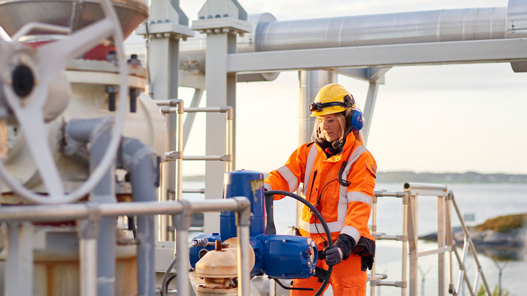 Female frontline worker looking at equipment at the Nyhamna Gas Plant (photo)