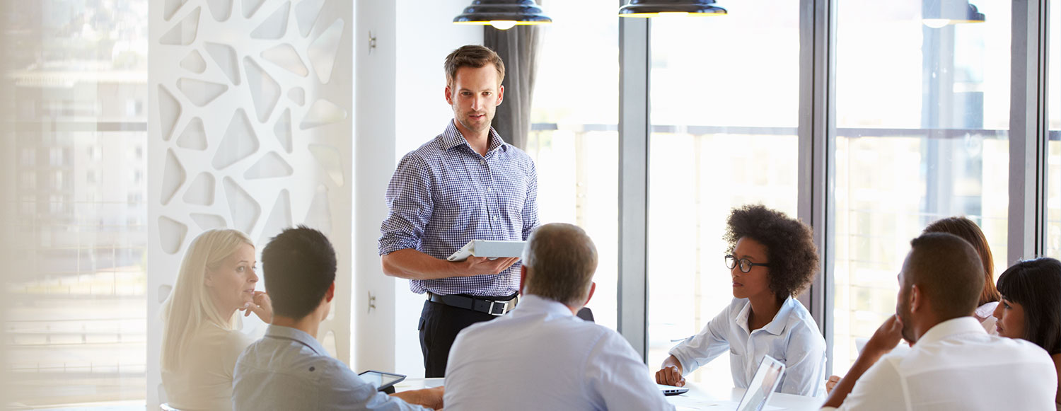 Man standing and presenting to colleagues at an office meeting (photo)