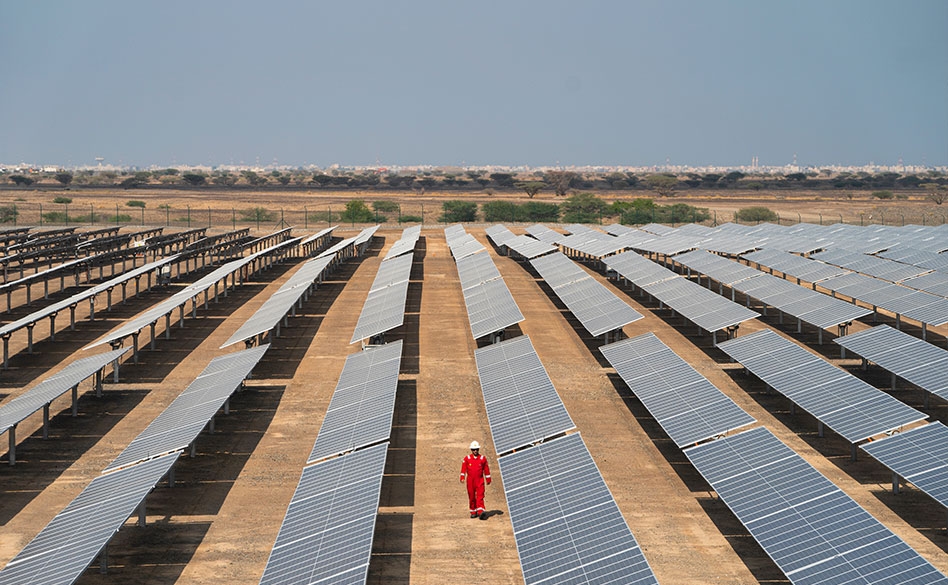 Solar engineer seen walking between rows of solar panels, at Sohar Solar Qabas, Oman (photo)