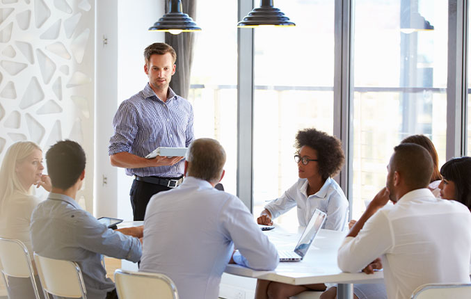 Man standing and presenting to colleagues at an office meeting (photo)