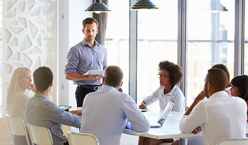 Man standing and presenting to colleagues at an office meeting (photo)