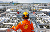 Shell employee standing in front of an array of metallic pipes
