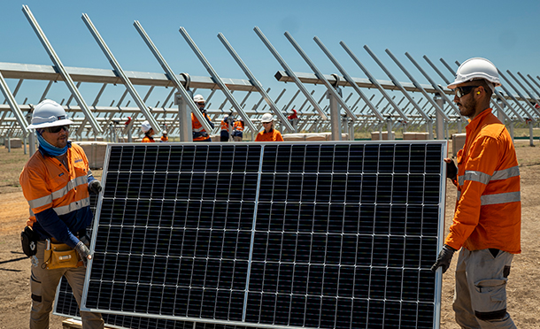 Two people carrying a solar panel at a newly built solar park