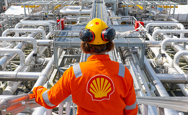 Shell employee standing in front of an array of metallic pipes
