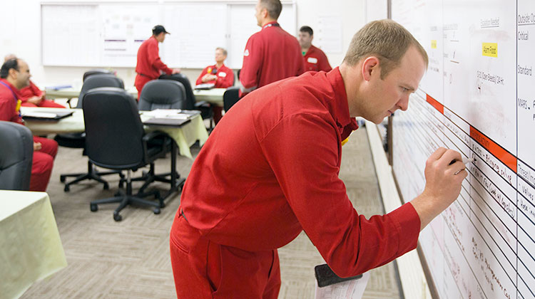 Several men wearing red overalls in a training class room (photo)