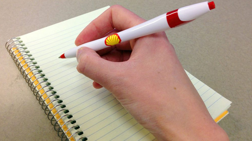 Hand holding a ball pen with Shell pecten on it (photo)