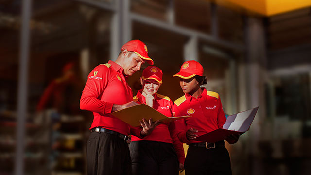 Three employees in red Shell clothes and cap (photo)