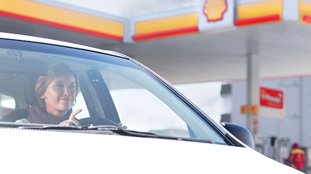 Woman in a white car infront of a Shell petrol station (photo)