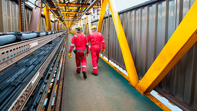 Two Shell personnel proceeding from Shearwater wellhead across the 80 metre bridge to Shearwater main platform, Aberdeen, UK (photo)
