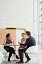 A group of three business executives holding a meeting in an office breakout area (photo)