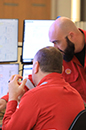 Group of three Shell workers in workwear overalls viewing information ona computer screen (photo)