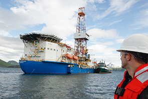 Worker in front of exploration vessel with a blue painted hull, Alaska, USA (photo)