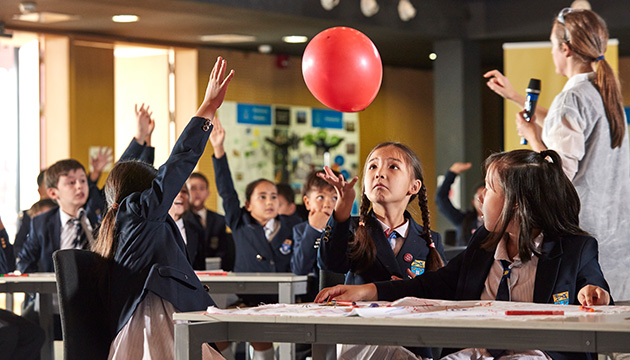 Kids playing with a balloon in a classroom (photo)