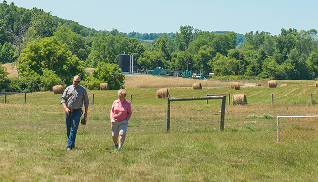Shell community liaison officer meets a landowner with a Shell well site in the distance in Appalachia, USA. (photo)
