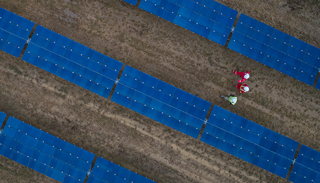 Bird's eye view of three workers walking in between solar panels at the Silicon Ranch solar power project in Nashville, Tennessee, USA. (photo)