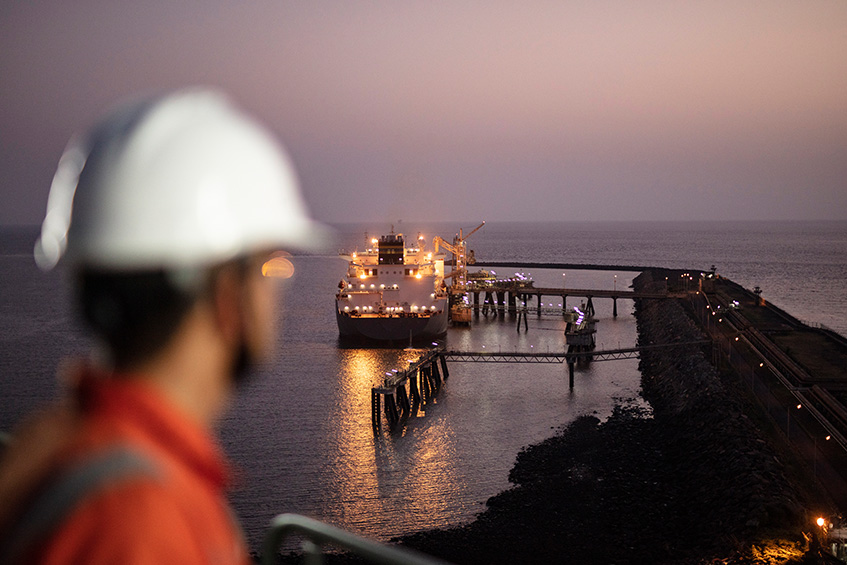 Worker looking at ship delivering cargo of liquefied natural gas to the Hazira regasification facility on the west coast of India. (photo)