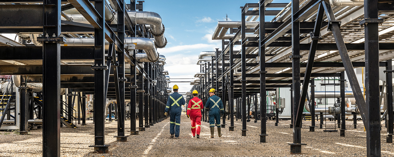 Employees walk in between equipment at the Montney Gas Plant at Shell Groundbirch Operations in Canada. (photo)