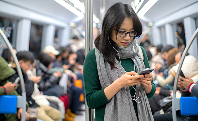 Young woman using her mobile phone on the train, China, 2019 (photo)
