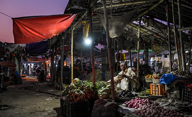 A market seller under electric light, powered by Husk Solar Power, India, 2018 (photo)
