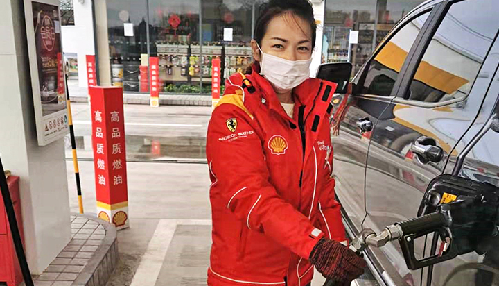 A Shell employee wearing a mask, filling up a vehicle with fuel at a service station in China. (photo)
