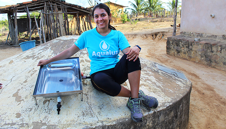 A woman sitting on top of a tank with a new water purification device in Brazil. (photo)