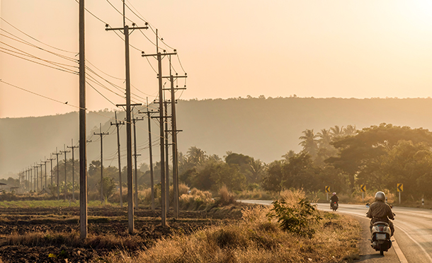View of electricity pylons near a road with two people on motorcycles (photo)