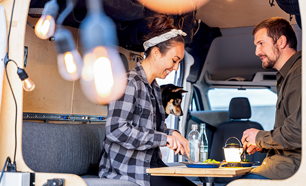 Woman, man and dog sitting in a van and having lunch (photo)