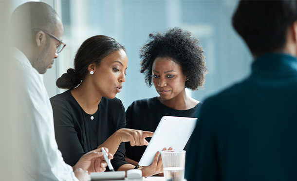 Two women discussing business in a meeting with others (photo)