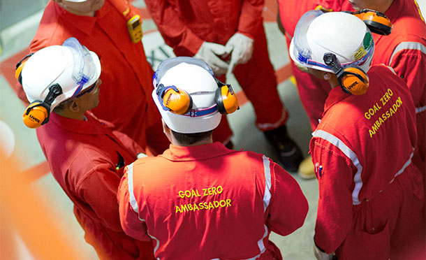 Group of Shell employees wearing hard hats and PPE having a safety briefing  (photo)