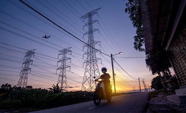 Motorcyclist riding past energy pylons at sunset (photo)