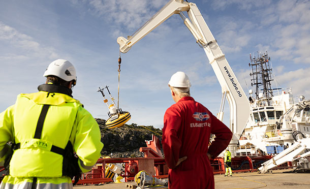Shell employee and supplier standing on a dock watching a crane during metocean survey (photo)