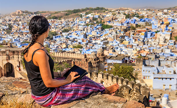 Female tourist ising digital tablet with the blue city of Jodhpur in the background. (photo)