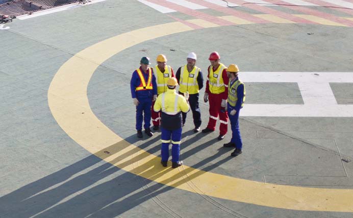 group of men wearing PPE having a Safety briefing on a helipad (photo)
