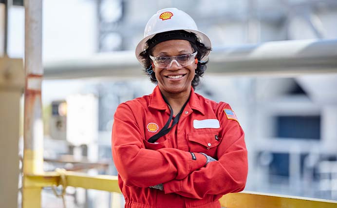 Smiling Shell employee in PPE with her arms crossed at Shell facility in USA (photo)