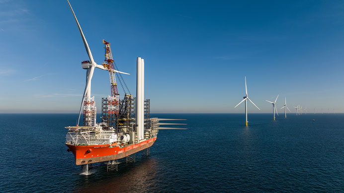 A vessel installs turbines at an offshore wind farm against a clear sky (photo)