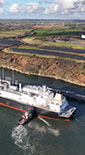 aerial photo of Shell LNG vessel next to pipeline and shoreline with tug boats around (photo)