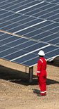 man wearing PPE standing next to solar panels (photo)