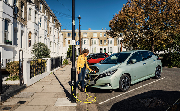 A woman charging an electric vehicle. (photo)